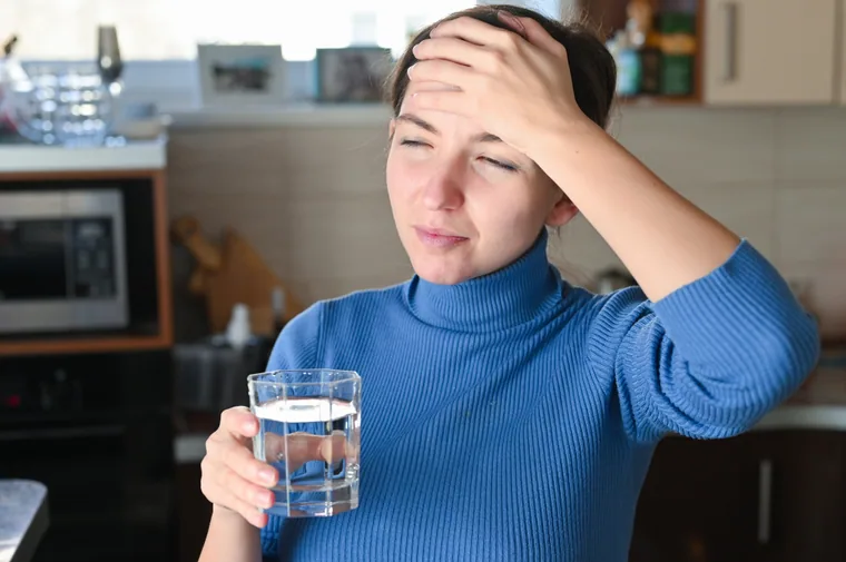 Young woman reacting to water taste in a kitchen